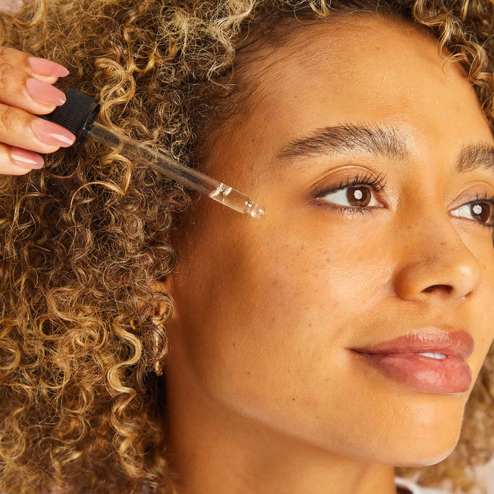A woman applying serum to her face